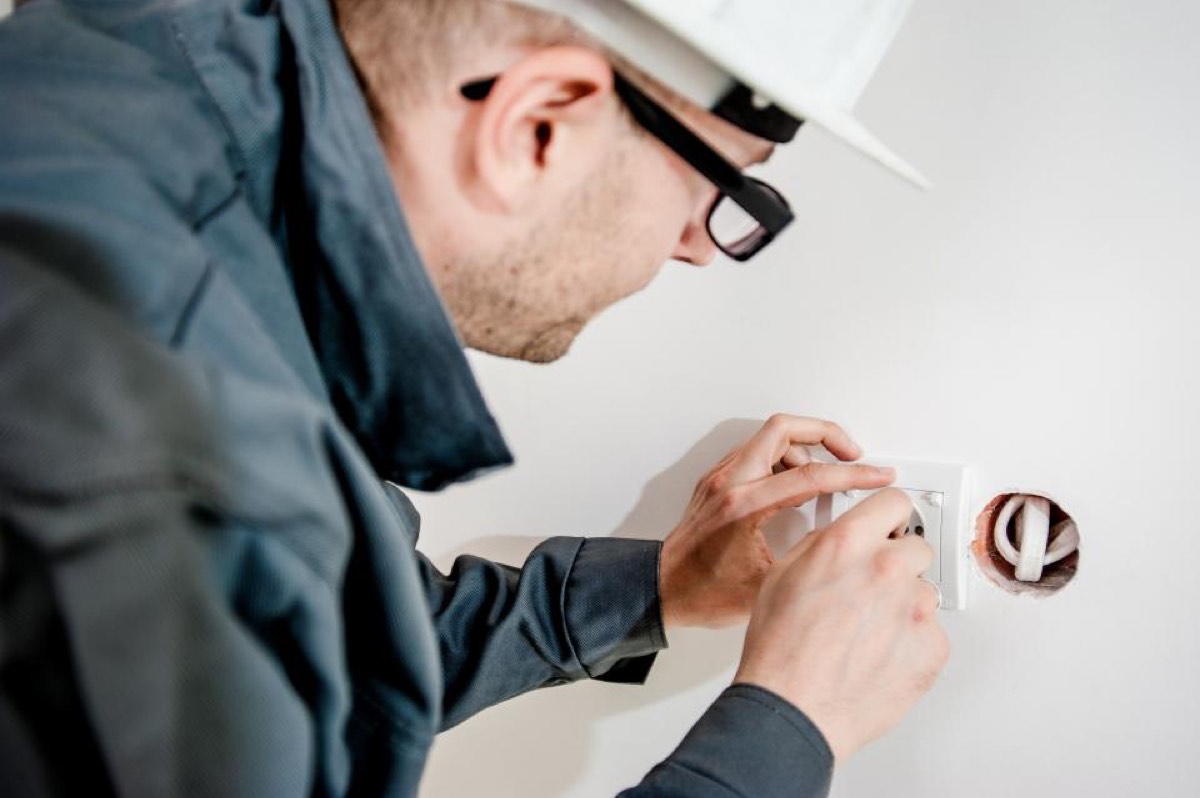 Technician replacing a wall outlet during a home service call